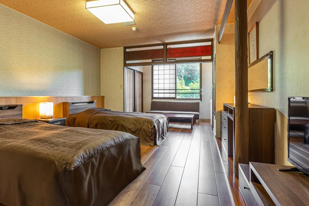 Une chambre d’hôtel avec deux lits, une télévision, un bureau et une fenêtre donnant sur un paysage agréable.