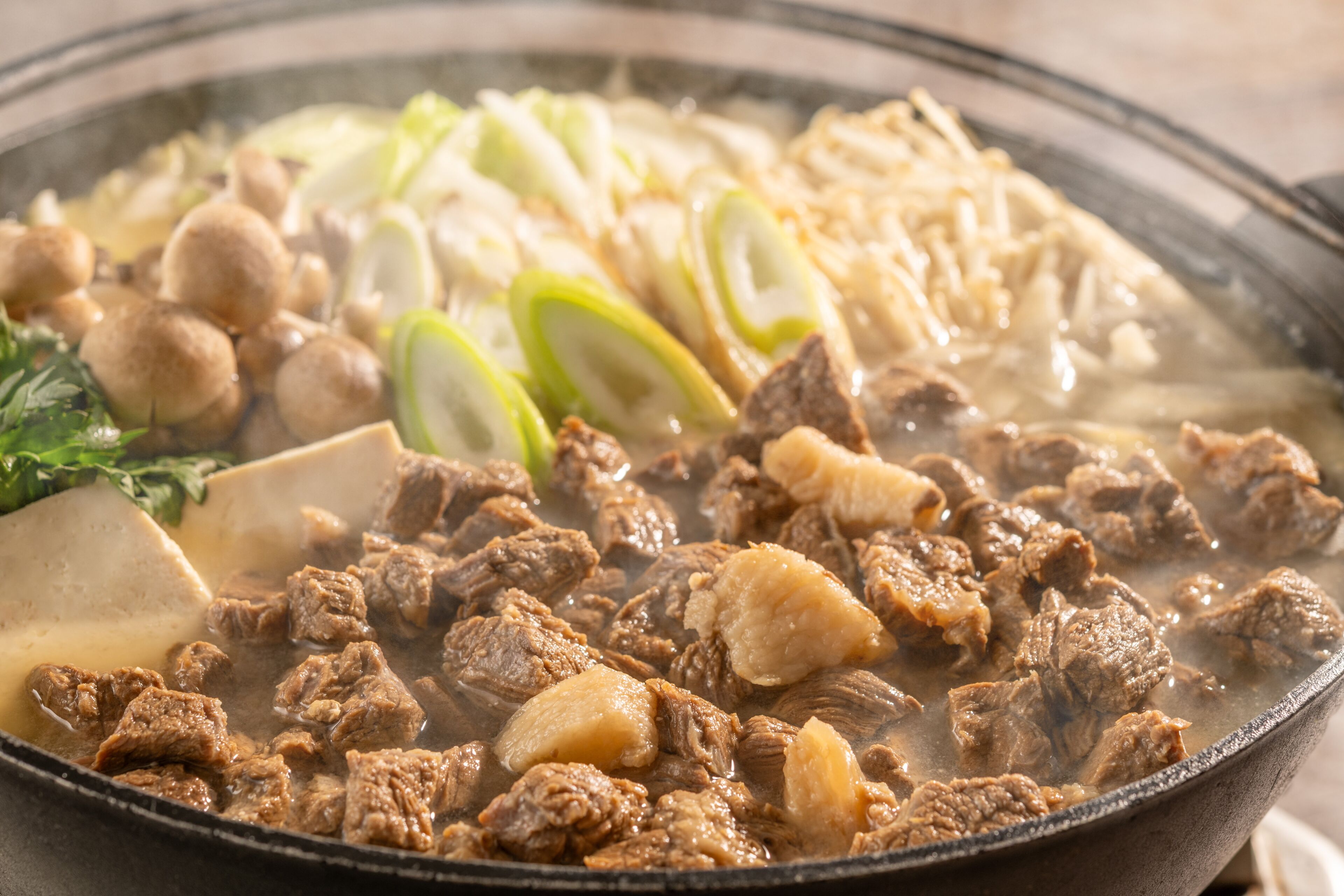 A hot pot with various ingredients including meat, vegetables, and dumplings.