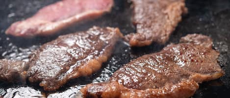 Steaks cooking on a grill.