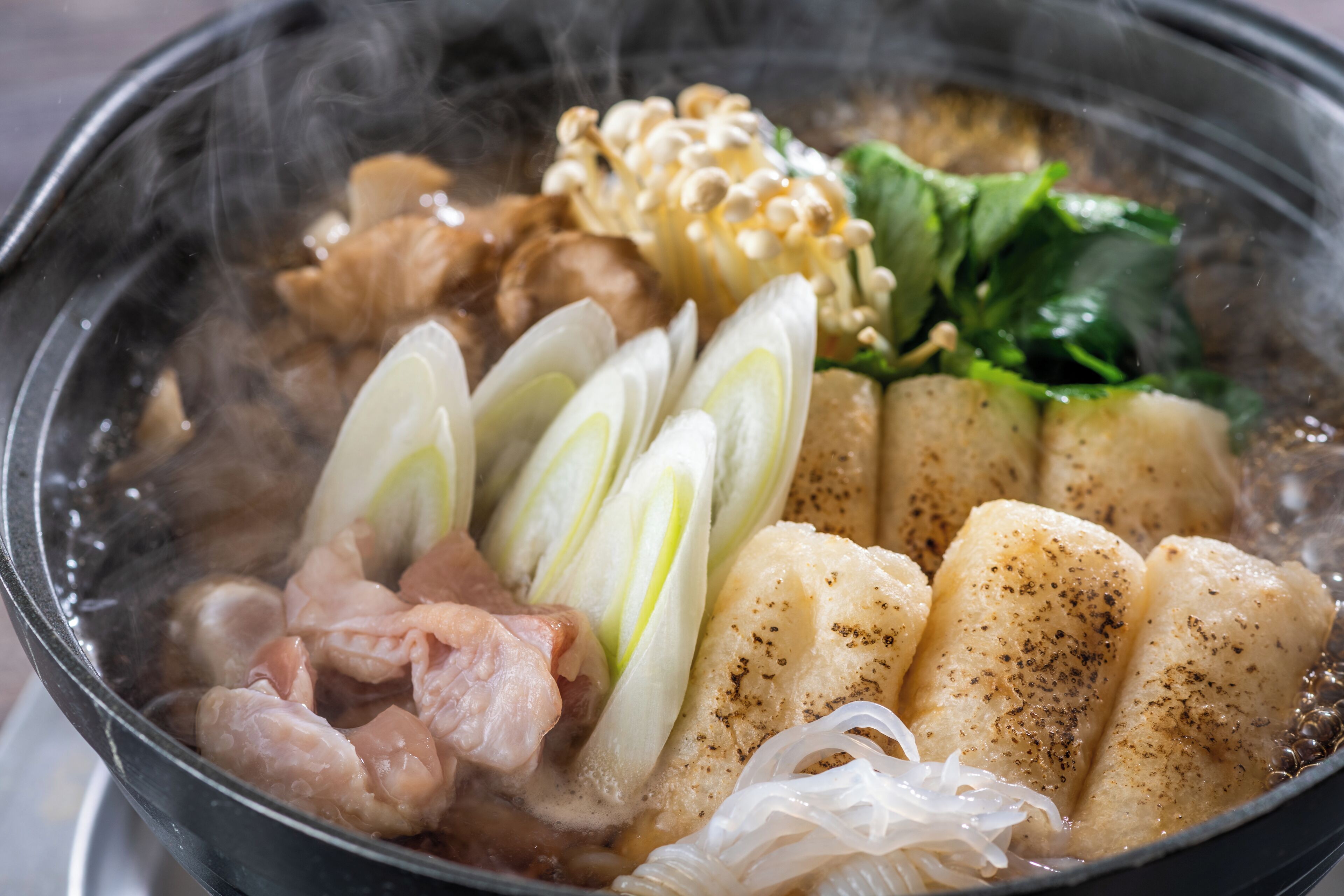 Ein heißes Pot mit verschiedenen Zutaten wie Fleisch, Tofu und Gemüse.