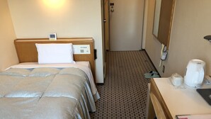 A hotel room with a bed, bedside table, and a small desk with a kettle and a cup. - Hotel Hikari Hills (Hikari)