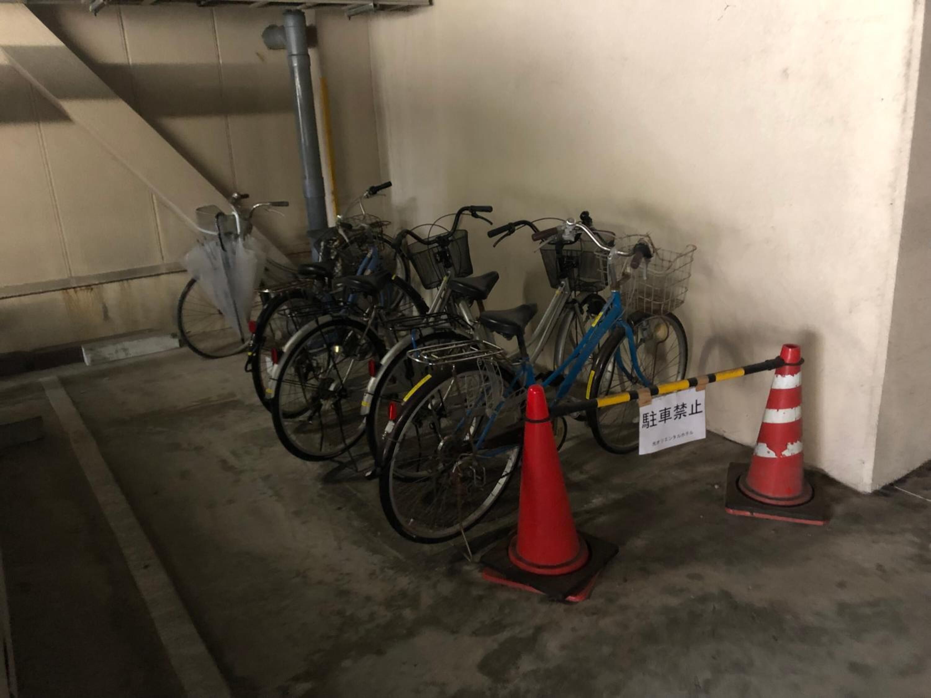 A parking area with bicycles parked in rows, a red traffic cone, and a sign with Japanese text.