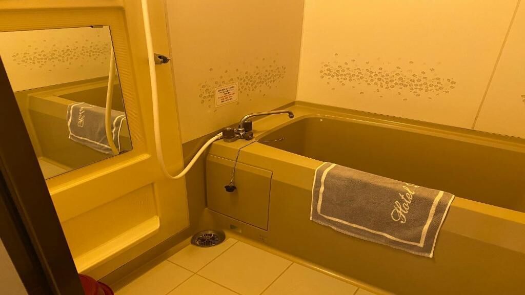 A bathroom with a bathtub, a towel hanging on the wall, and a mirror.