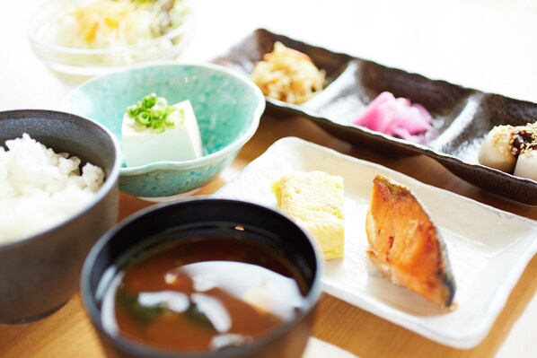 Variedad de platos japoneses, como arroz, tofu y pescado, presentados en distintos platos y recipientes.