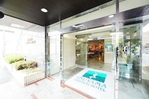 La entrada del Hotel Central Inuyama, con una puerta de vidrio transparente, un cartel en el suelo y vistas al área del vestíbulo.