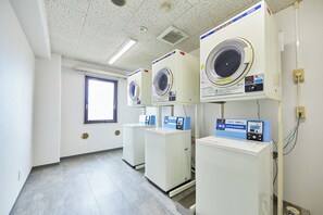 Un lavadero con tres lavadoras apiladas y un panel de control.