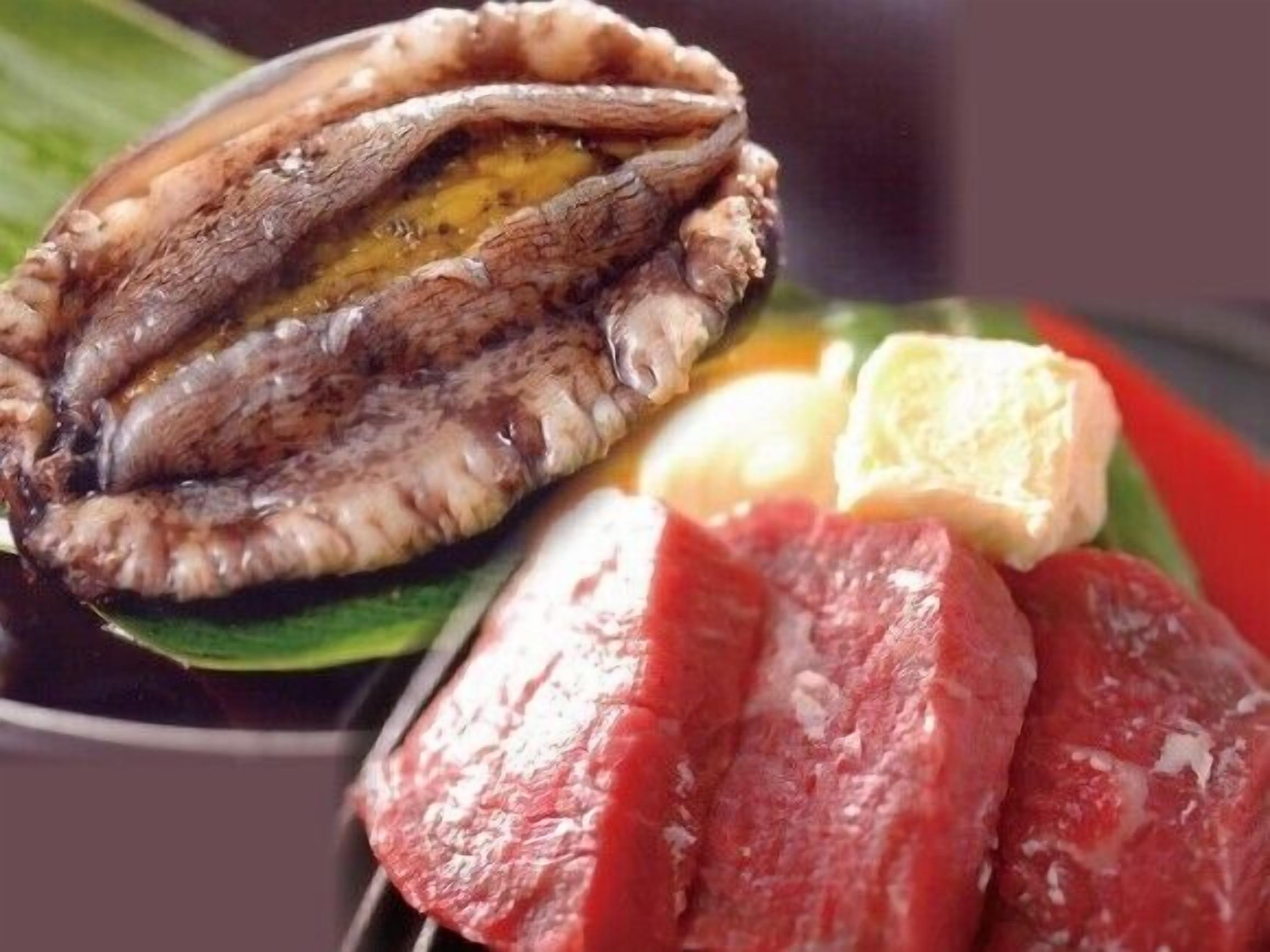 Un plato con marisco cocido, rebanadas de carne y un gajo de limón.
