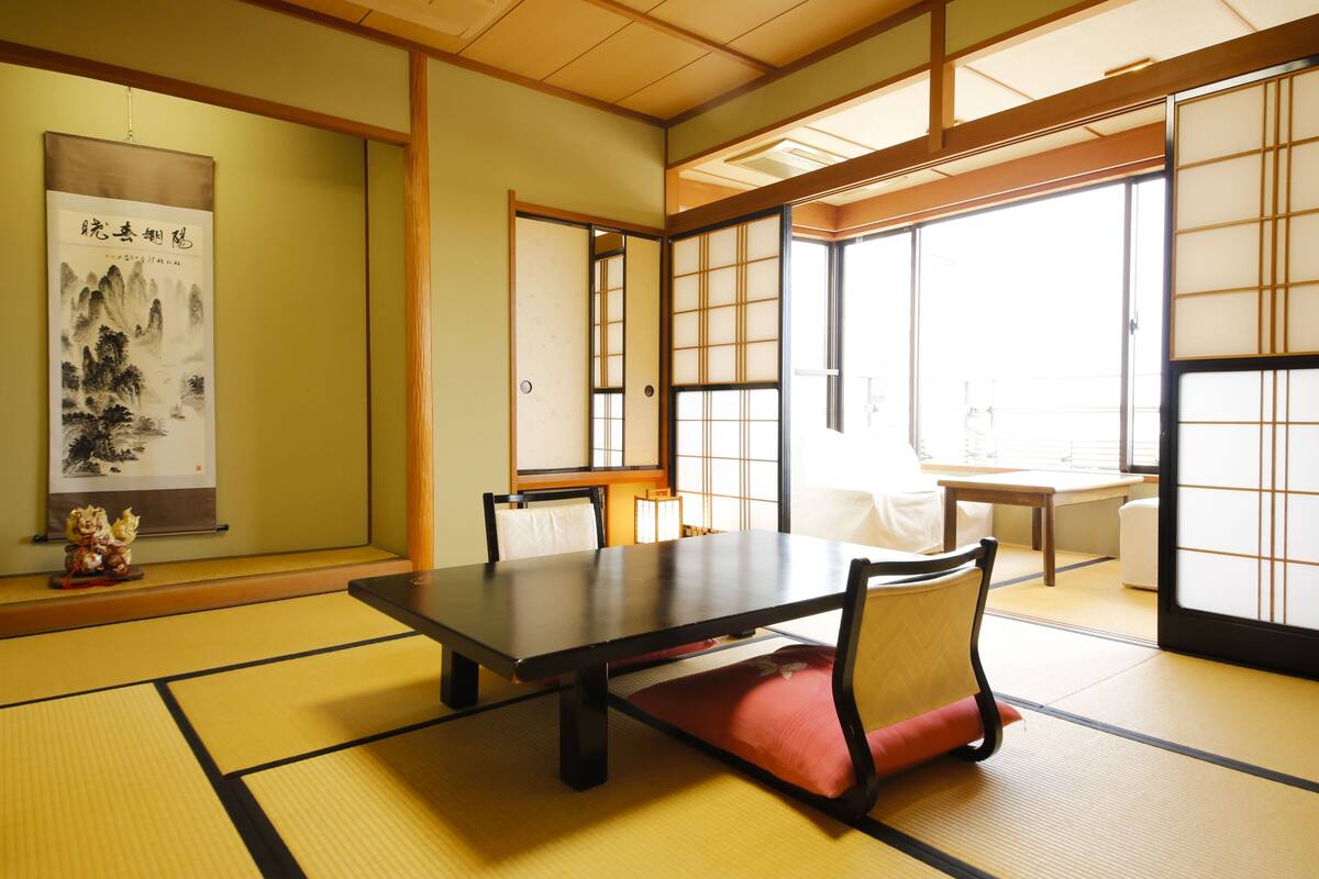 Una habitación japonesa tradicional con suelo de tatami, una mesa baja y puertas correderas.