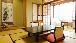 Una habitación japonesa tradicional con suelo de tatami, una mesa baja y puertas correderas.