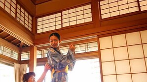 Una habitación japonesa tradicional con suelo de tatami, puertas correderas y techo de madera.