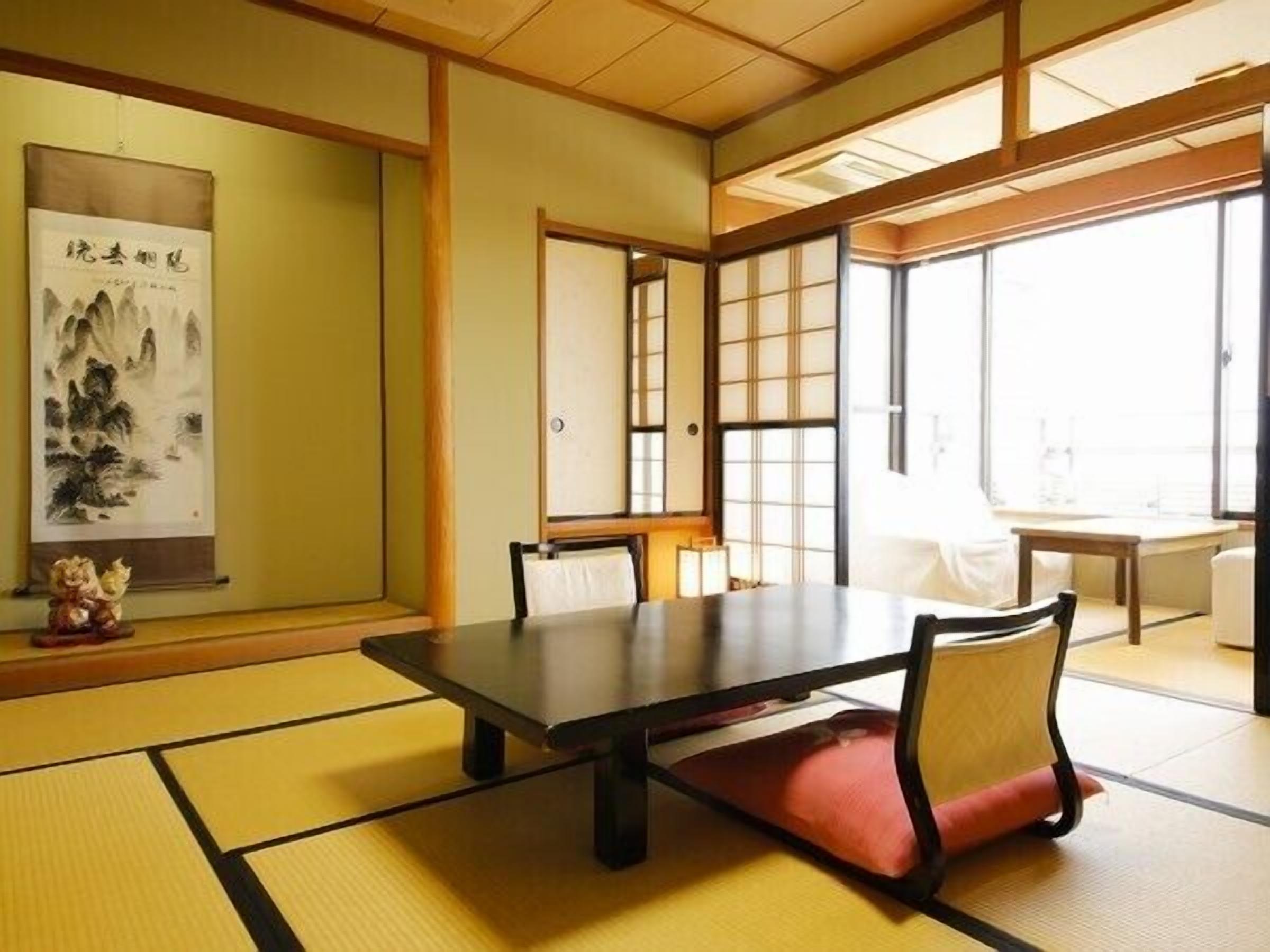 Ein traditioneller japanischer Raum mit Tatami-Böden, einem niedrigen Tisch und verschiebbaren Türen.