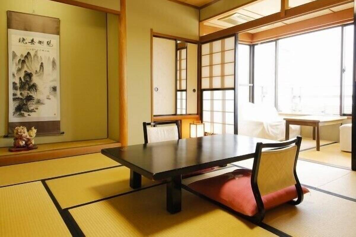 Una habitación japonesa tradicional con suelo de tatami, una mesa baja y puertas correderas.