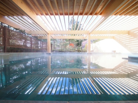 An indoor swimming pool with a wooden ceiling and a view of the outdoors.