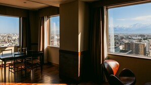 A modern hotel room with a large window offering a city view and mountains in the distance. - Oarks canal park hotel Toyama (Toyama)