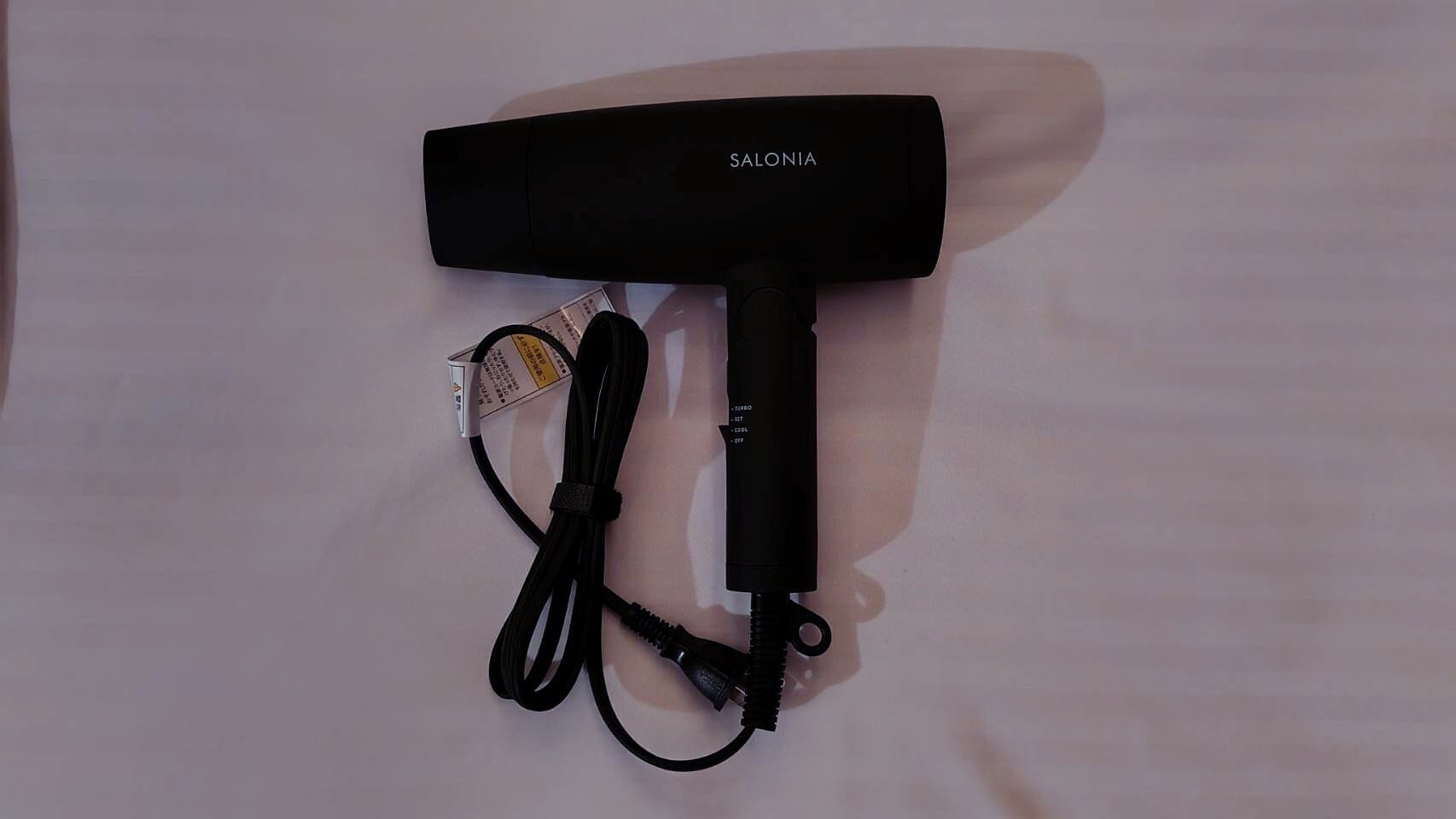 Un sèche-cheveux noir avec un câble et un adaptateur secteur.