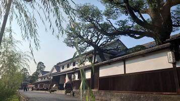 Um edifício japonês tradicional com cerca de madeira, uma bandeira e uma placa com caracteres japoneses.