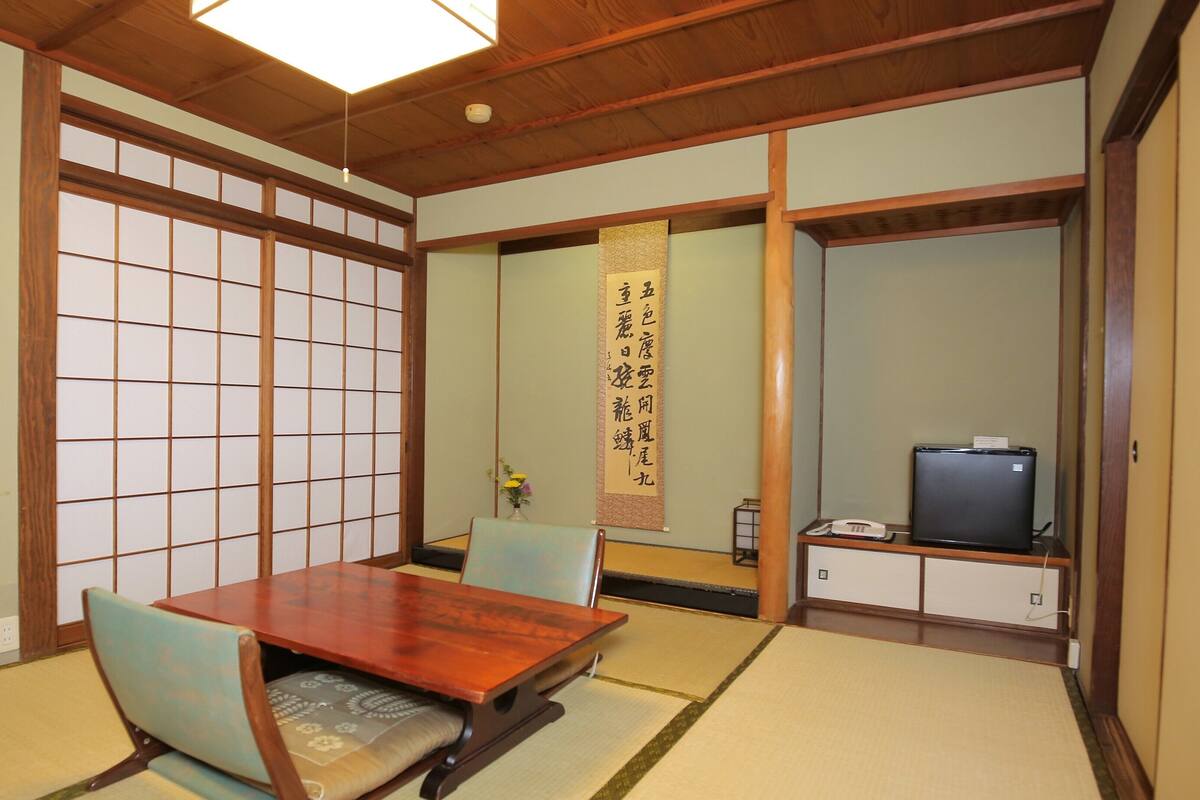Une pièce de style japonais traditionnel, avec un sol recouvert de tatamis, une table en bois et des chaises.