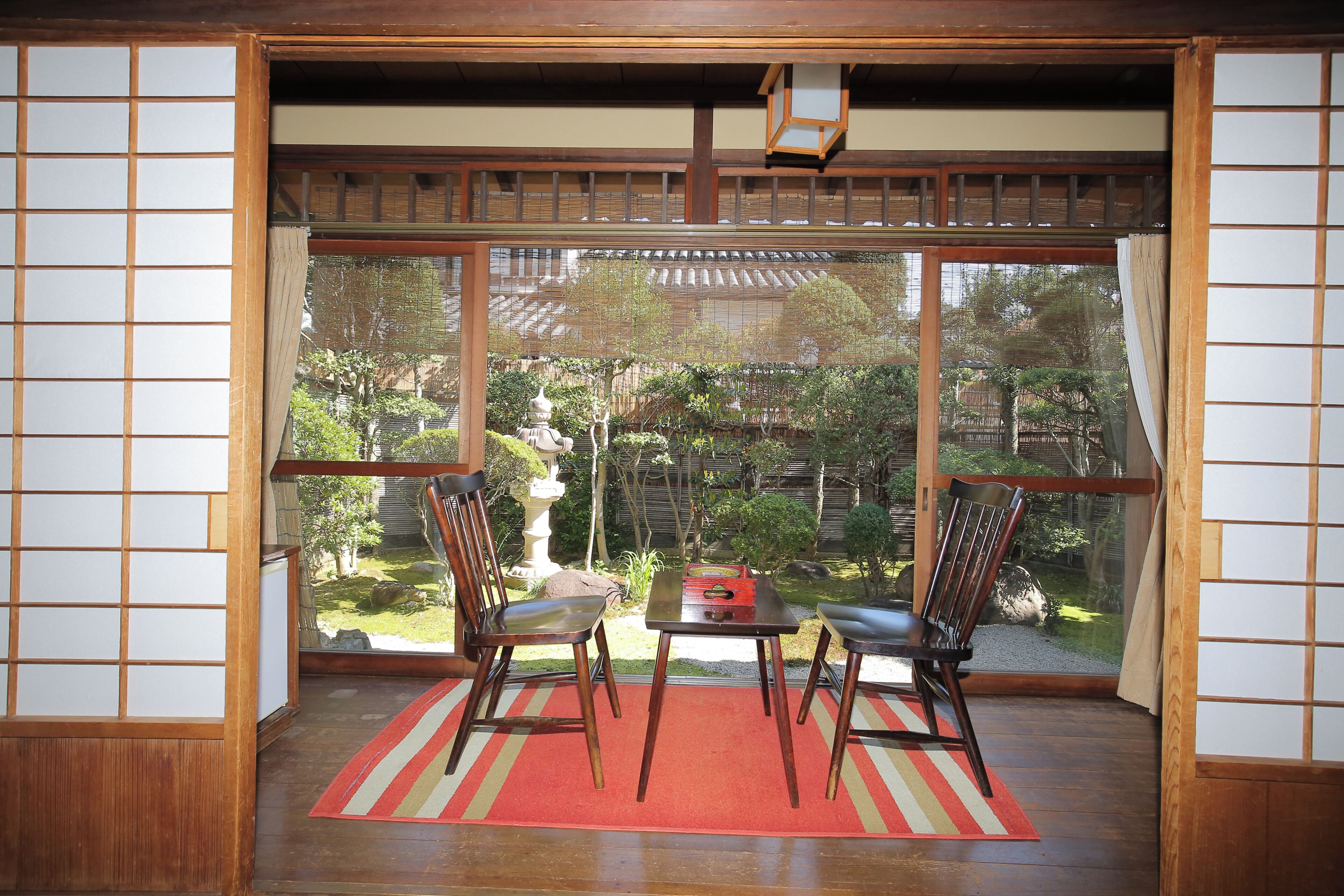 A traditional Japanese room with tatami flooring, a low table, and two chairs.