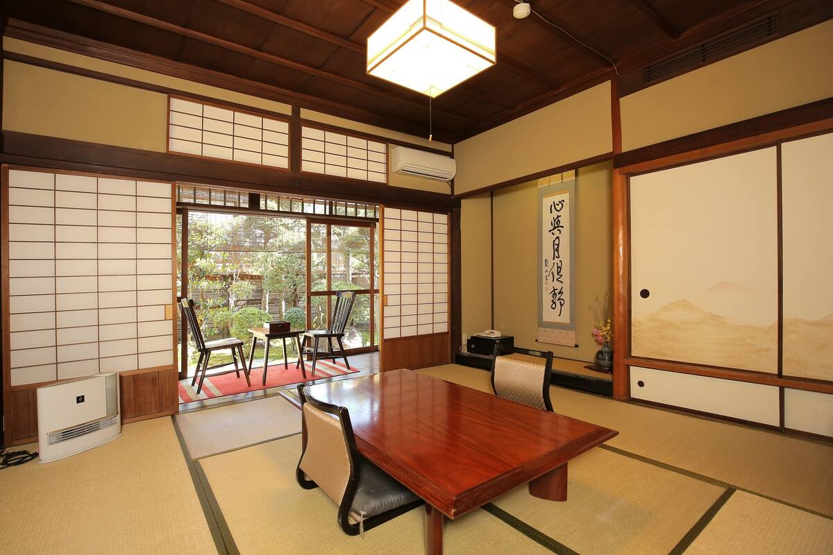 Une pièce de style japonais traditionnel, avec un sol recouvert de tatamis, une table en bois et des portes coulissantes.