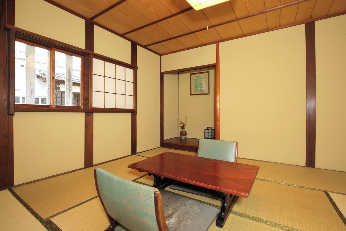 Une pièce de style japonais traditionnel, avec un sol recouvert de tatamis, une table en bois et deux chaises.