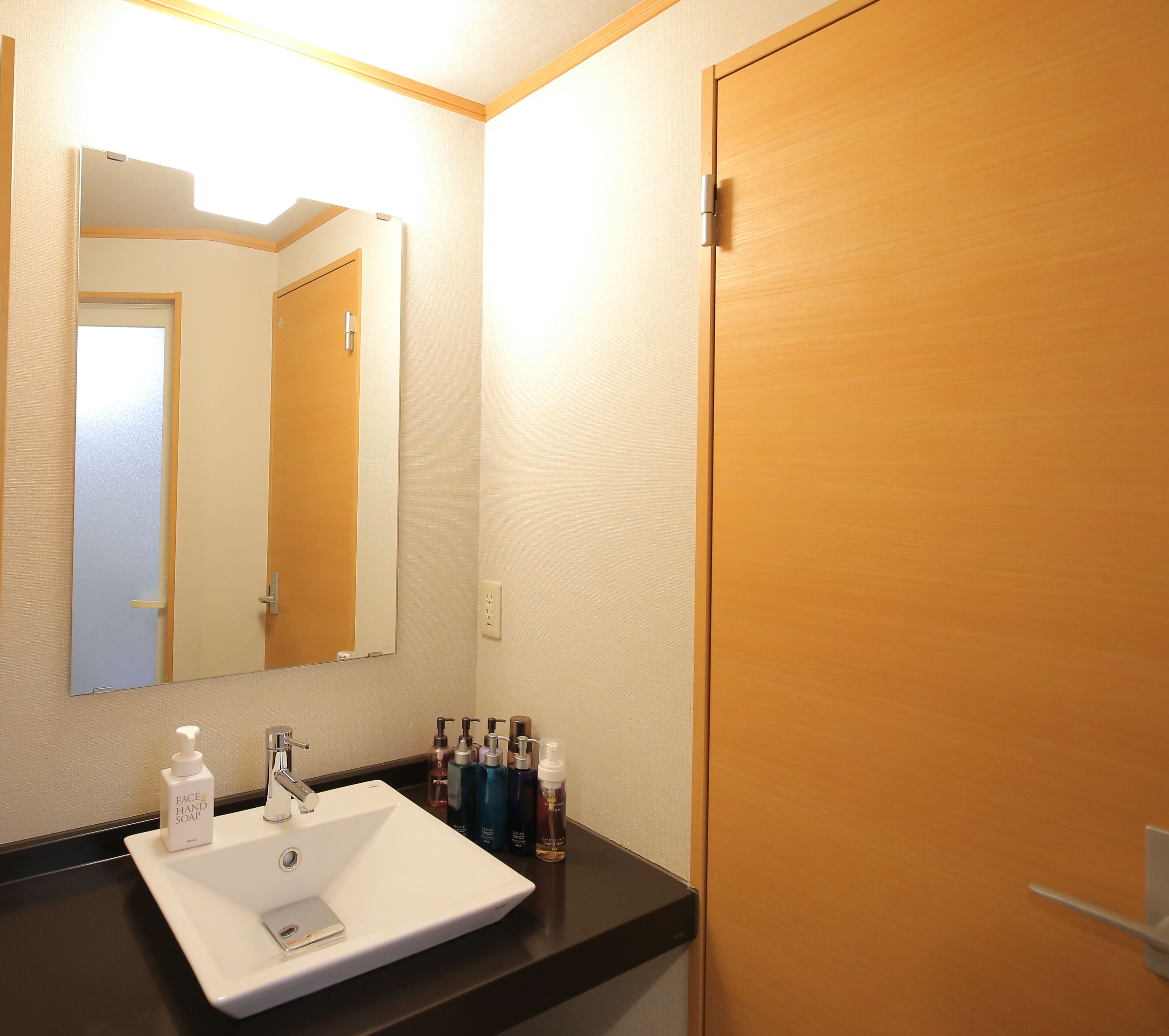 Un baño de hotel con un lavabo blanco, un espejo y artículos de aseo en la encimera.