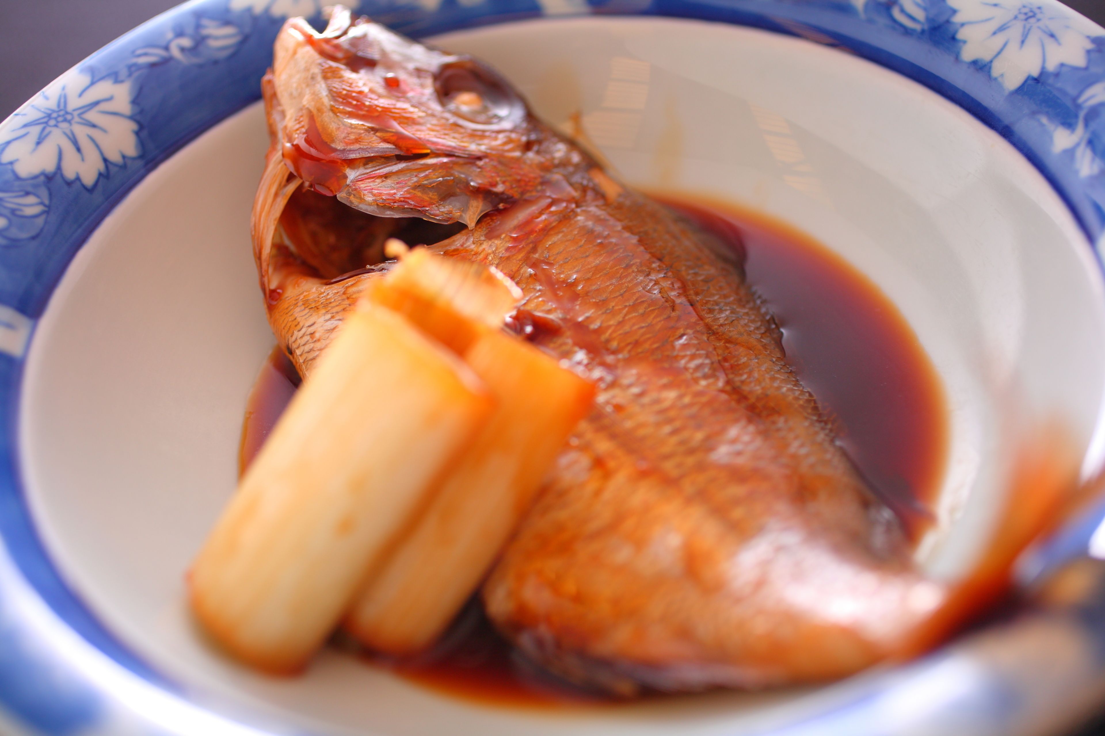 A bowl of fish with bones and sauce.