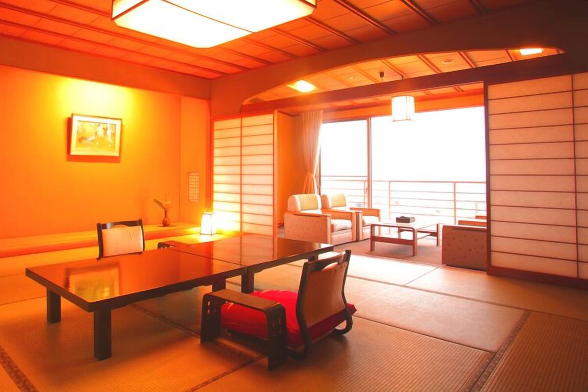 Ein traditioneller japanischer Raum mit Tatami-Bodenbelag, einem niedrigen Tisch und einer Couch.