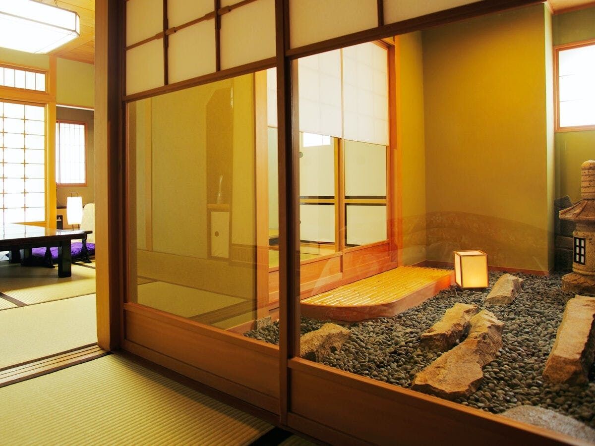 Una habitació japonesa tradicional amb tatami, una taula de fusta baixa i un petit jardí de roques.