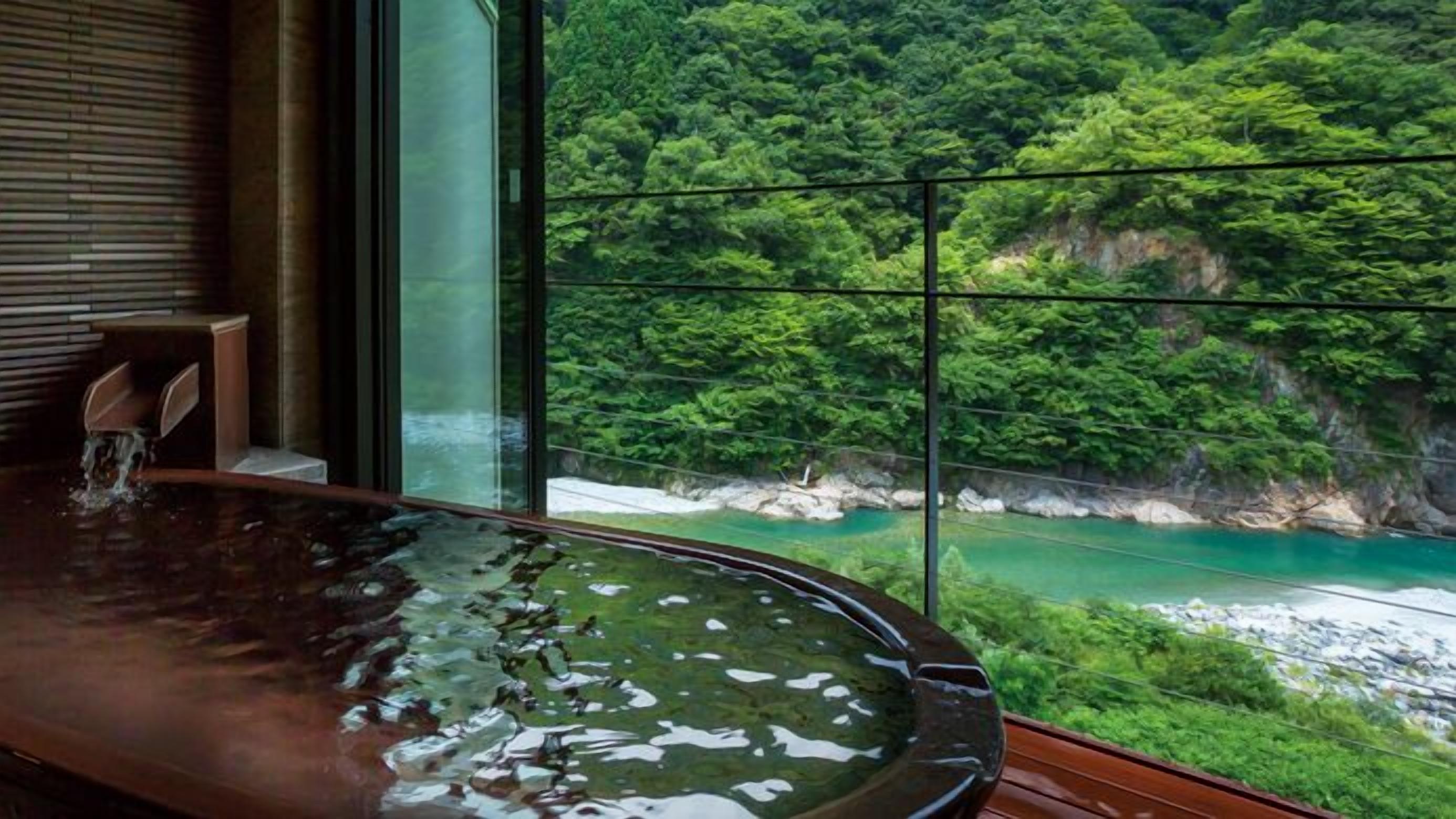 Jacuzzi amb vista a un penya-segada boscosa i un riu turquesa.