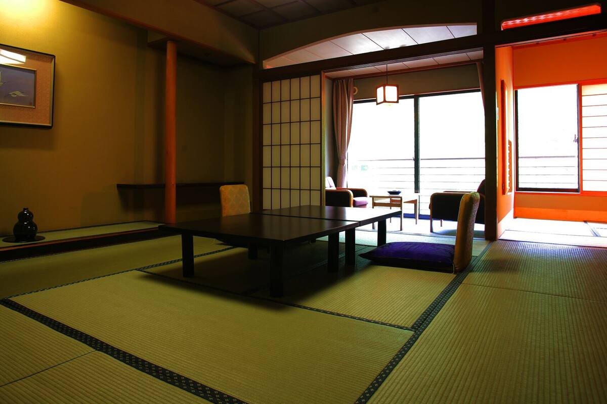 A traditional Japanese room with tatami flooring, a low table, and sliding doors.