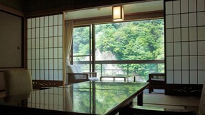 Una habitación japonesa tradicional con suelo de tatami, una mesa baja y puertas correderas.