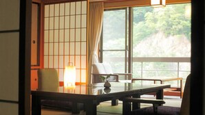 Una habitación tradicional japonesa con suelo de tatami, una mesa baja y un sofá.