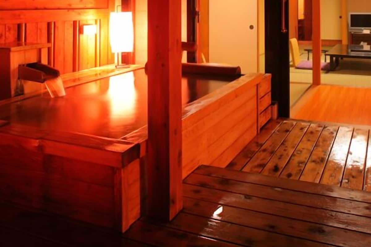 A wooden interior with a bench, a table, and a lamp.