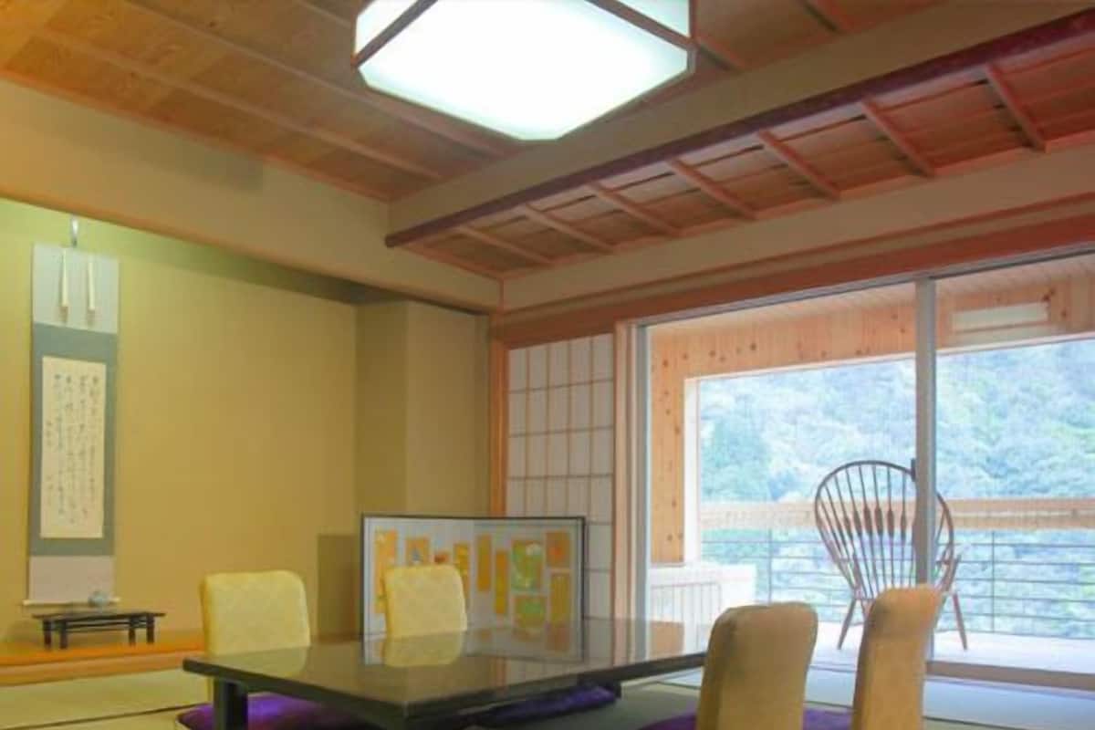 A tatami mat room with a low table, chairs, and a large window.