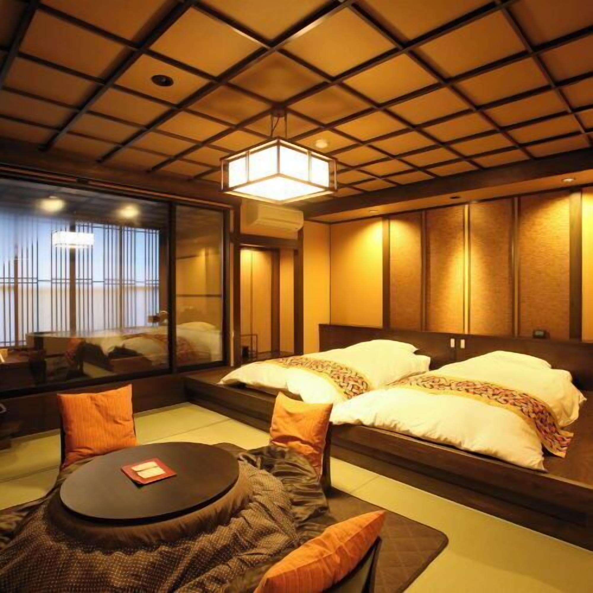 A traditional Japanese-style room with tatami flooring, a low table with cushions, and a bed with pillows.
