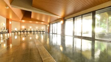 A spacious indoor area with a polished floor, large windows, and a wooden ceiling.