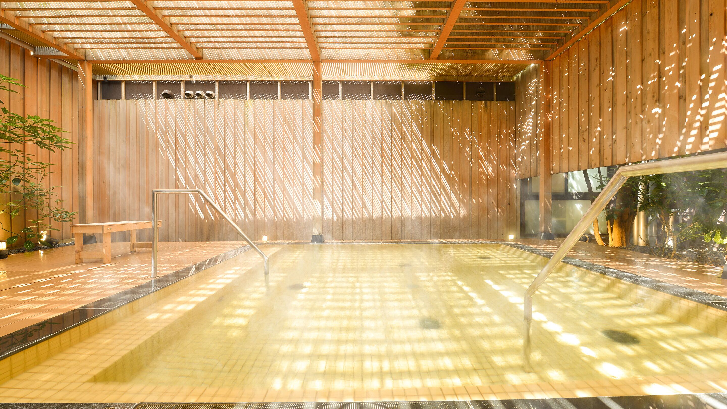 Zona de baño de aguas termales con vigas de madera y suelo de baldosas.