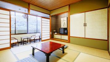 A traditional Japanese room with tatami flooring, a low table, a television, and sliding doors.
