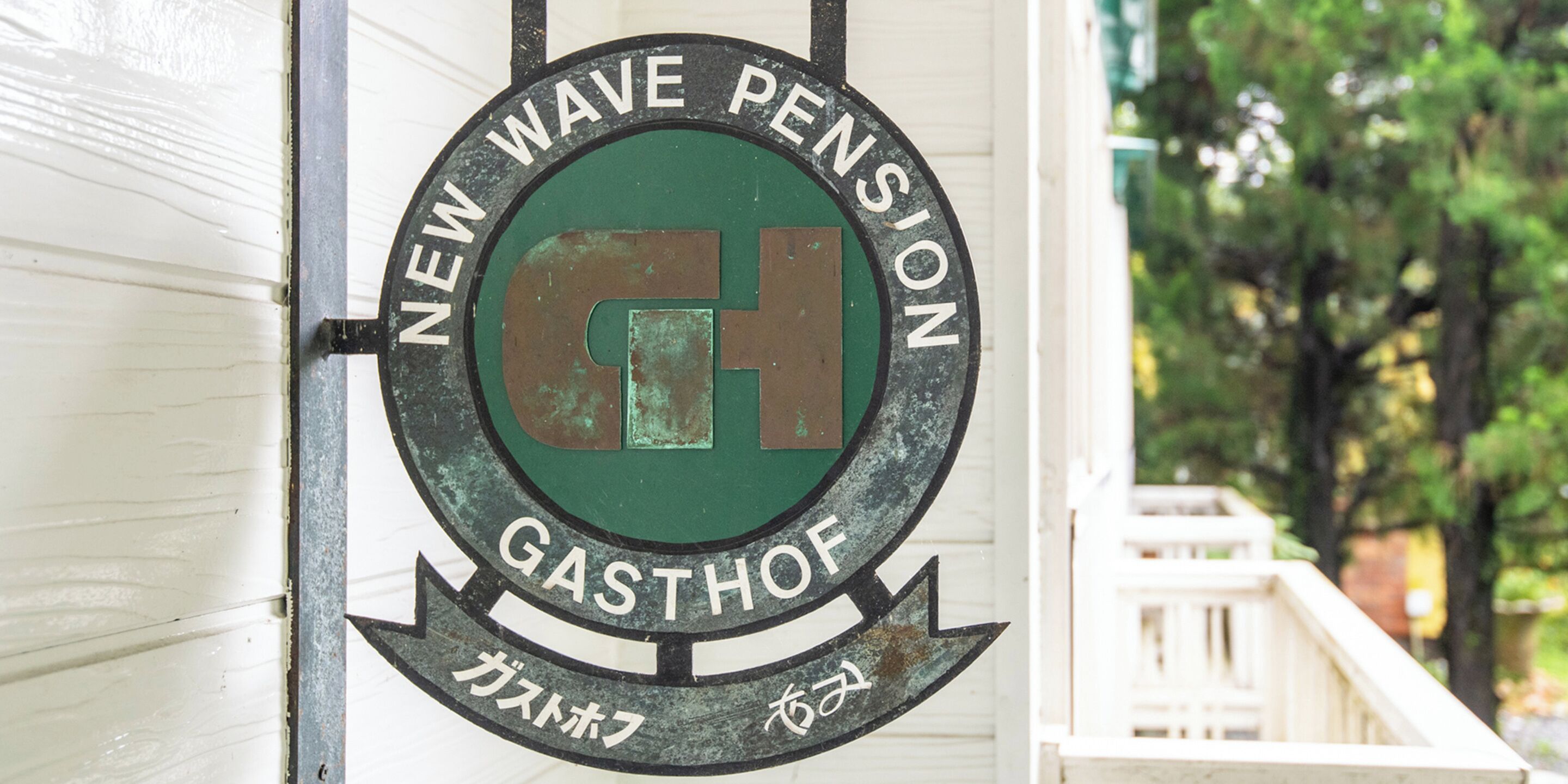 A circular sign with the text "NEW WAVE PENSION" and "GASTHOF" on it.