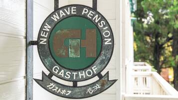 A circular sign with the text "NEW WAVE PENSION" and "GASTHOF" on it.