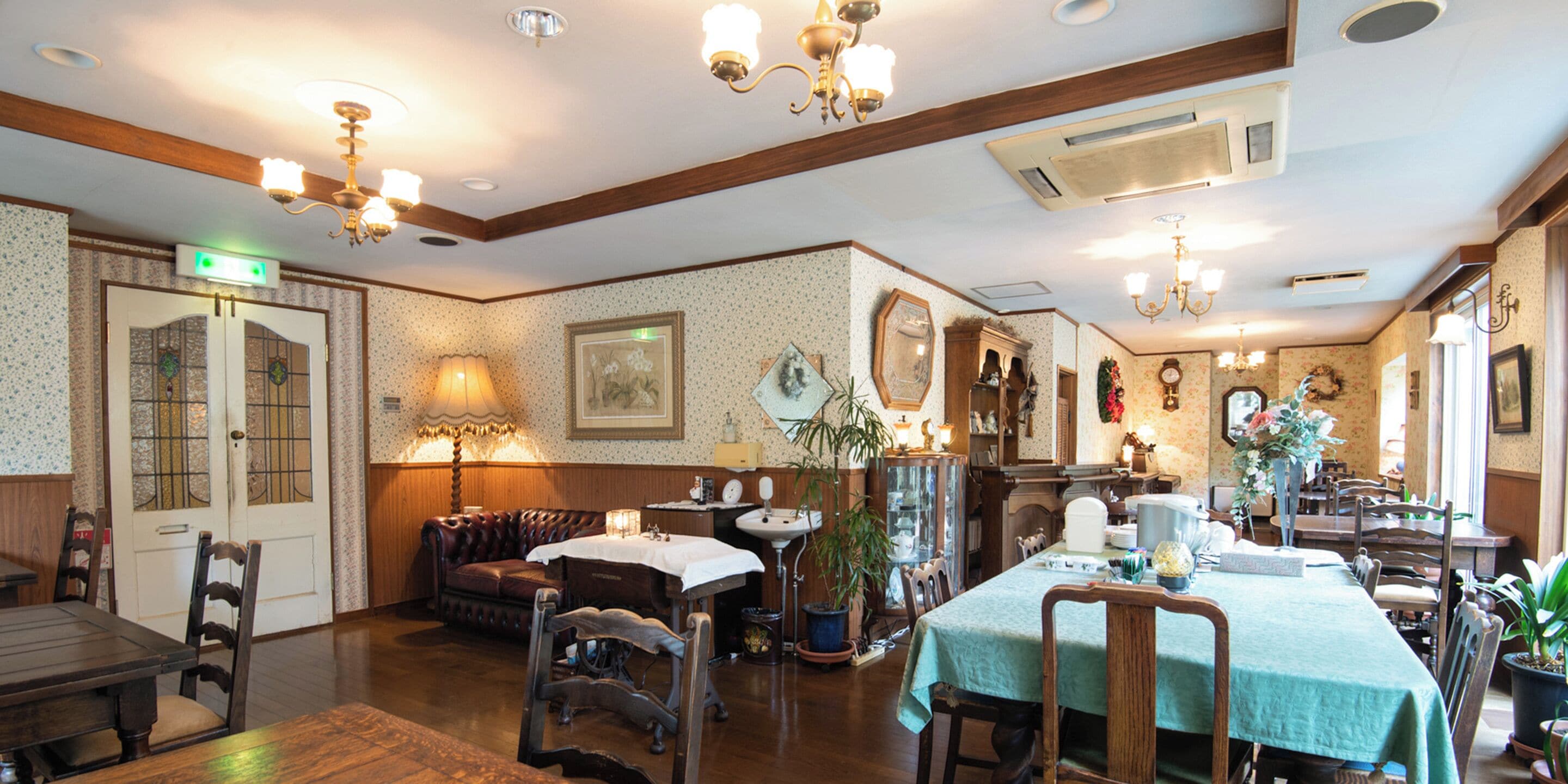 A traditional dining area with wooden furniture, a green tablecloth, and a chandelier.