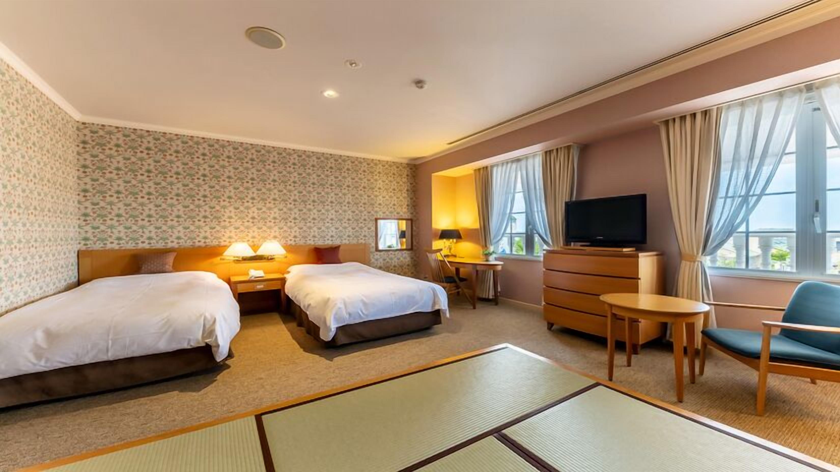 A hotel room with two beds, a TV, a desk, and a chair.
