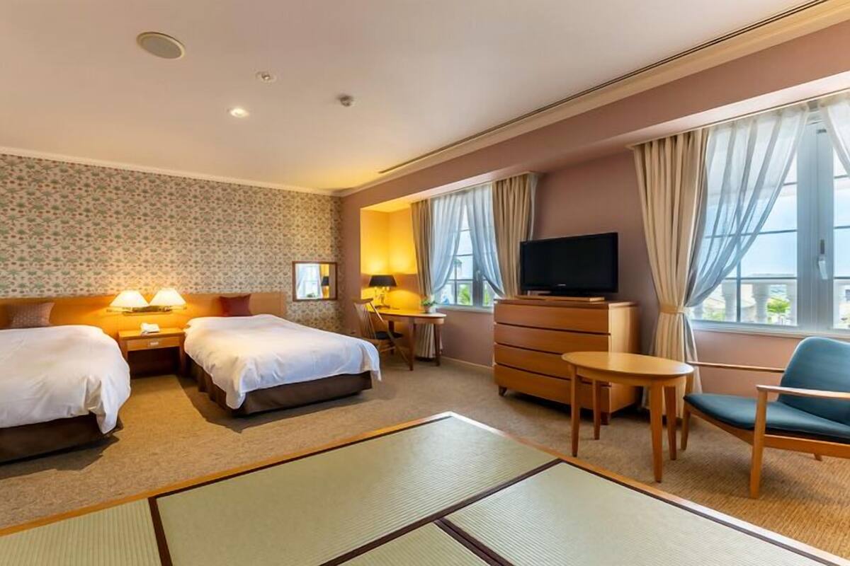 Habitación de hotel con dos camas, televisión, escritorio y silla.