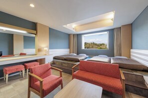 Habitación de hotel con cama, escritorio, silla, mesa y ventana con vista a una colina.