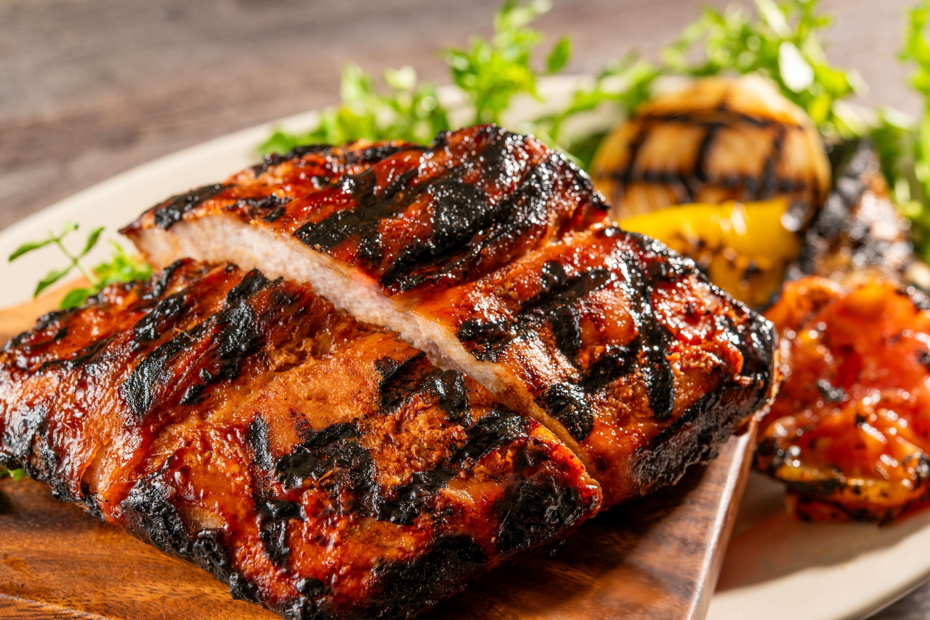 En grillad fläskkotlett med lätt brända kanter, serverad med grillade grönsaker och en klick sås.