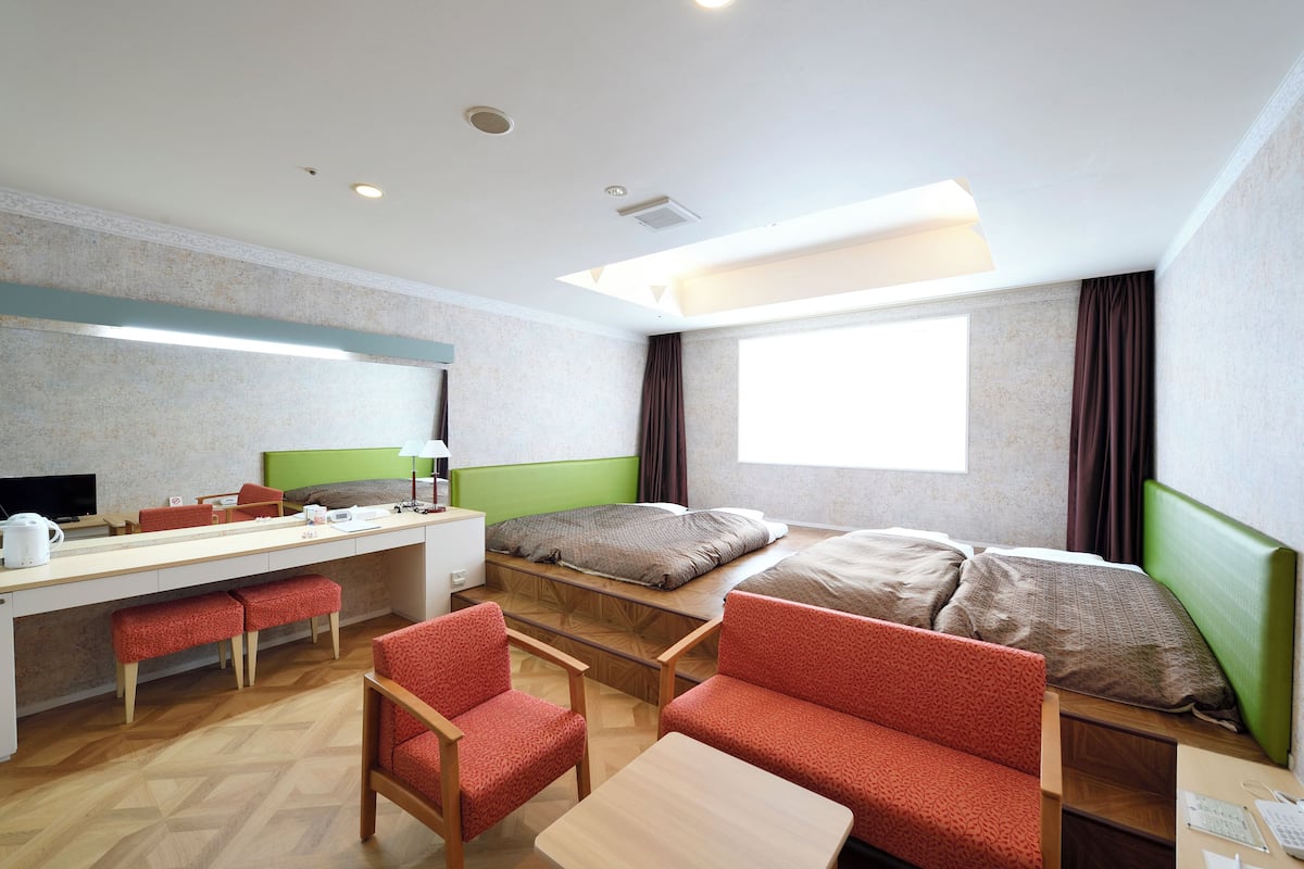 A hotel room with a bed, desk, chairs, and a window.