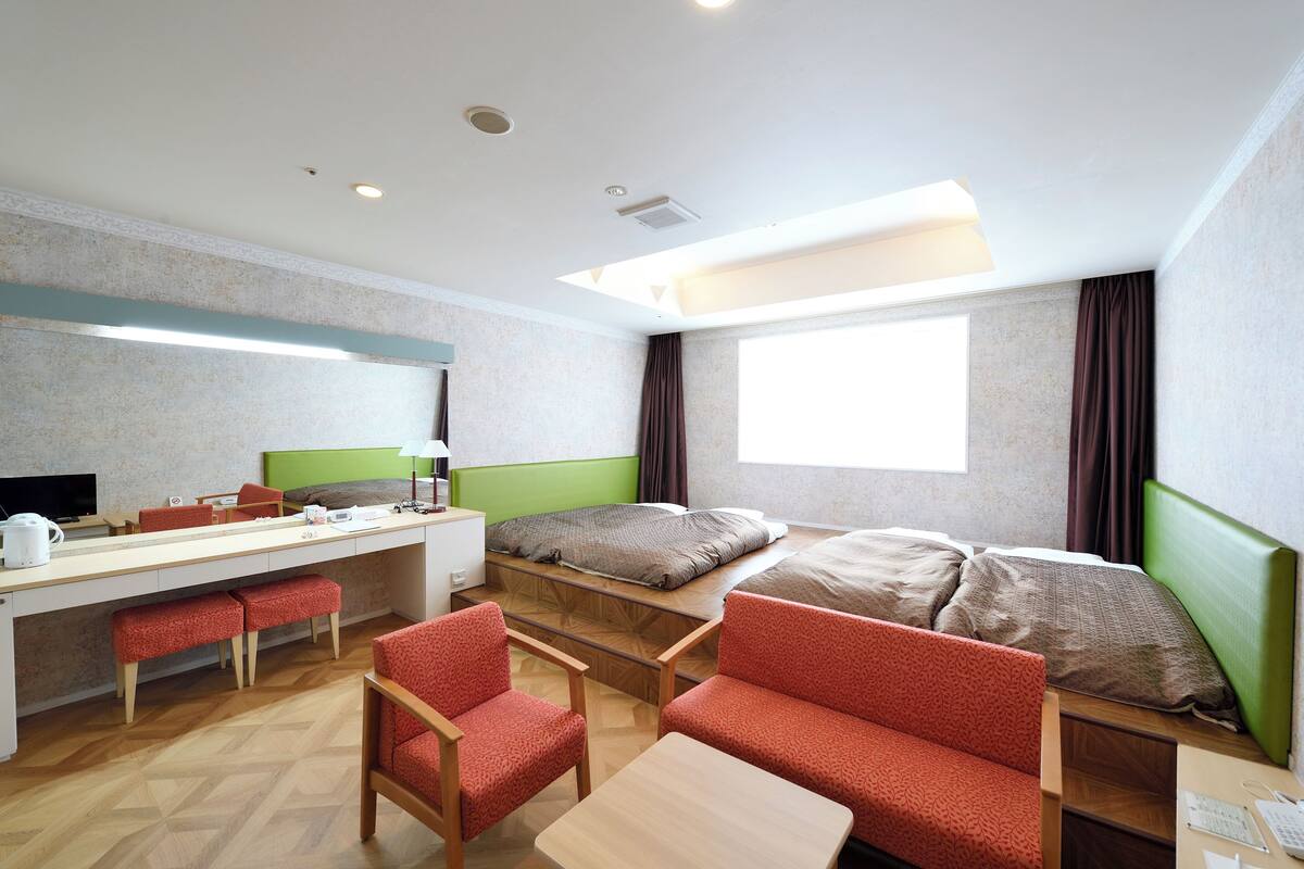 Habitación de hotel con cama, escritorio, sillas y ventana.