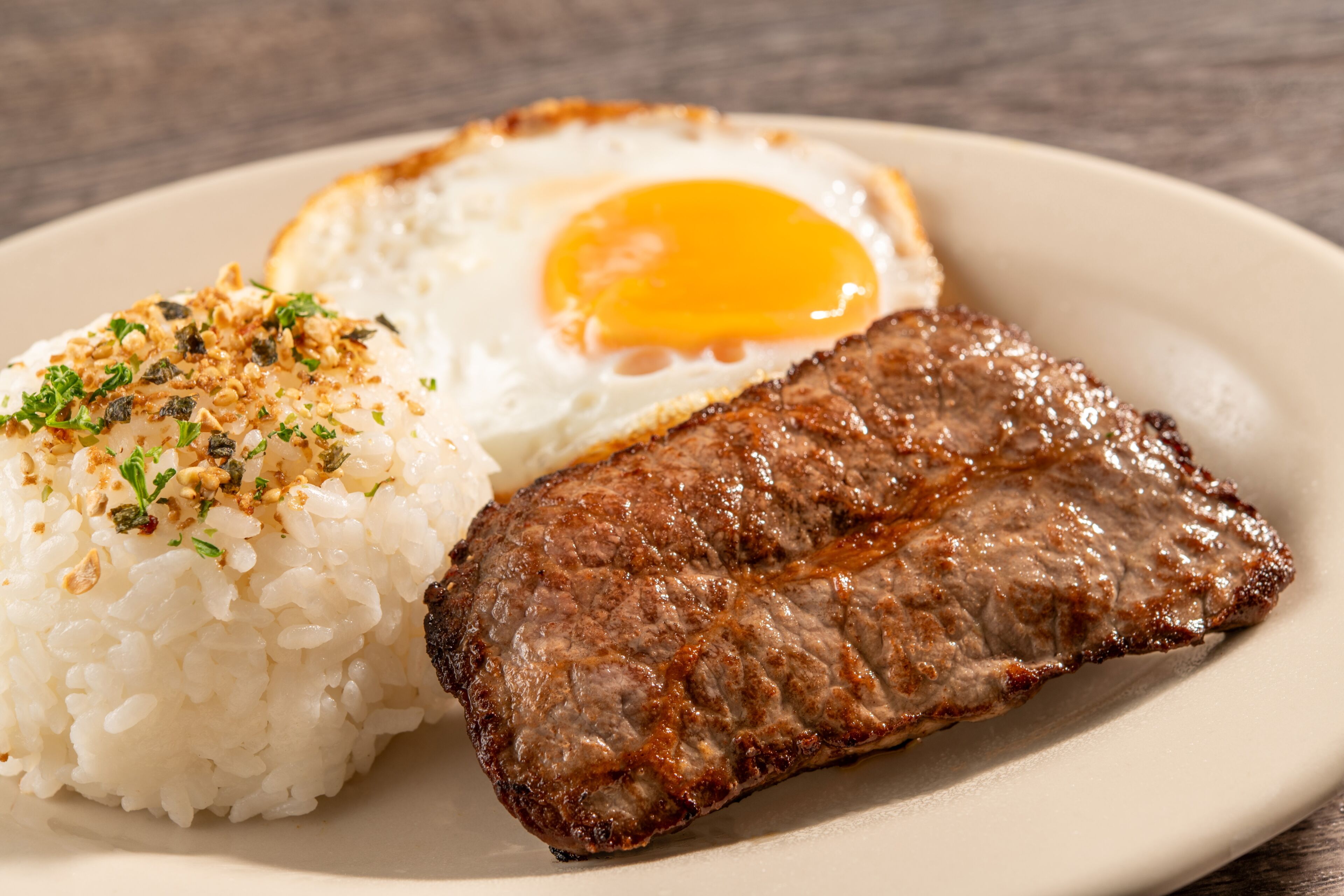 A plate with a grilled steak, fried egg, and white rice.