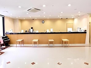 A hotel reception area with a counter, several chairs, and a clock on the wall. - Hotel Kawaroku Her-stage (Takamatsu)