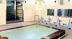 A swimming pool with a metal ladder, a glass door leading outside, and a row of small sinks with faucets. - Hotel Kawaroku Her-stage (Takamatsu)